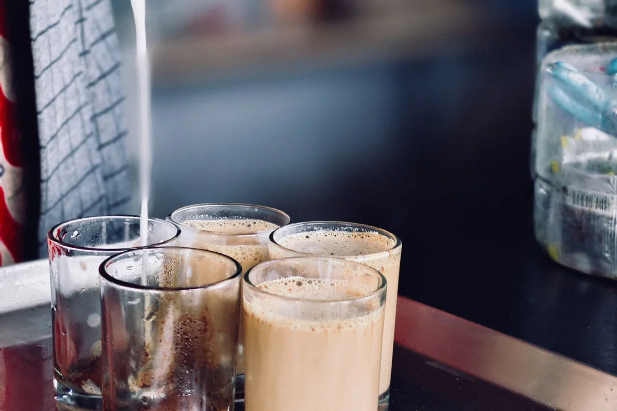 Chai being strained into small glasses at a stall