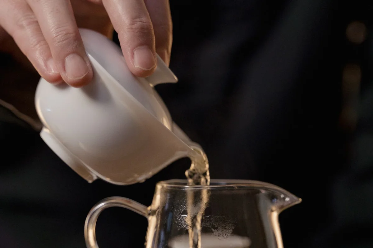 Tea being poured from a gaiwan into a glass serving pitcher