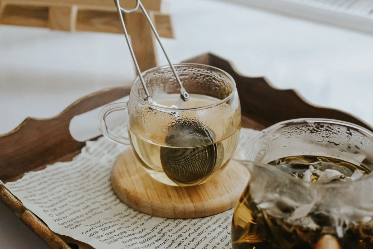 Glass teacups and a tea infuser on a wooden serving tray