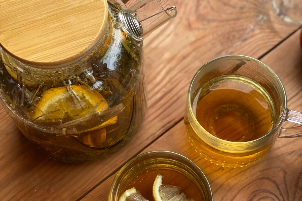 Glass cups and a pot of tea with lemon slices