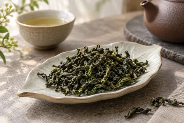 Long loosely twisted green Baozhong leaves on a pale dish