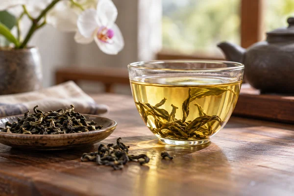 Pale gold tea with long twisted oolong leaves and one orchid out of focus