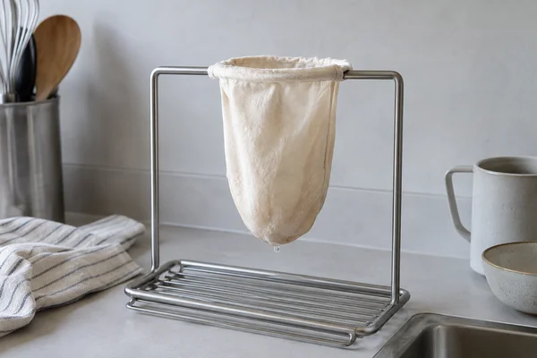 A cotton tea filter hanging from a metal drying rack