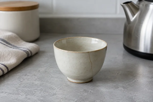 Empty ceramic cup with a fine visible crack on a dry table