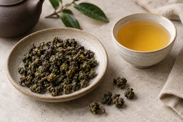 Rolled brown-green Dong Ding leaves beside honey-coloured tea