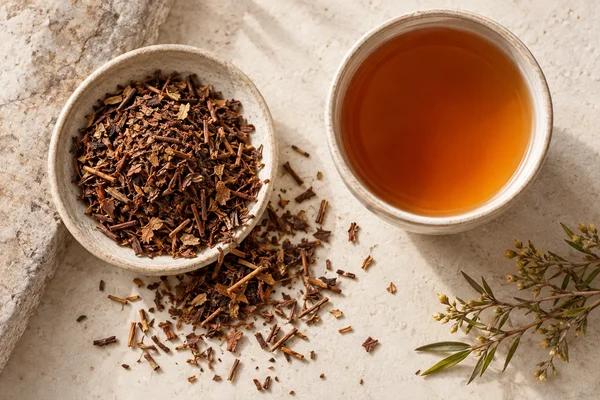 Chopped brown honeybush leaves and stems with an amber infusion