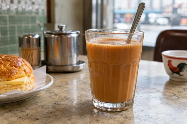 Hong kong cafe glass of brown tea coffee milk blend with stainless spoon