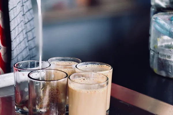 Chai being strained into small glasses at a stall