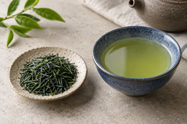 Fine green kabusecha leaves beside light green tea in a low blue bowl
