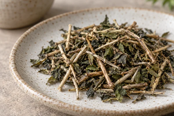Pale tea stems mixed with small dark green leaf pieces on a plate