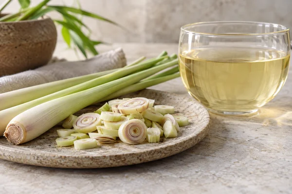 Cut lemongrass stalks and dried pieces beside a pale golden infusion