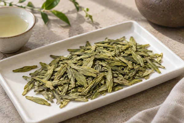 Flat yellow-green Longjing leaves spread across a white tray
