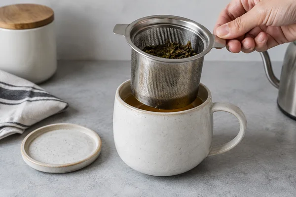 Large removable infuser basket lifted from a wide ceramic mug