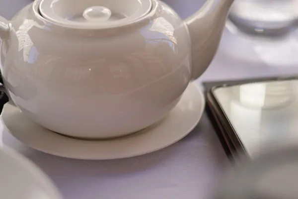 A plain white porcelain teapot on a table