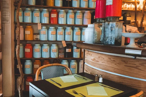 Tea shop with filled containers on the wall and a small table