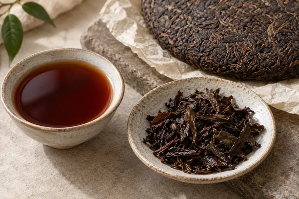 Dark ripe pu-erh leaves, a cake and reddish-brown tea