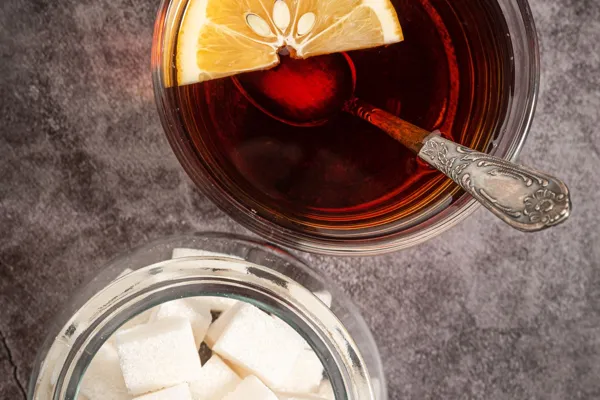 Tea with lemon beside a jar of sugar cubes