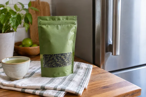 Sealed green tea packet resting outside a refrigerator with dry towel beneath