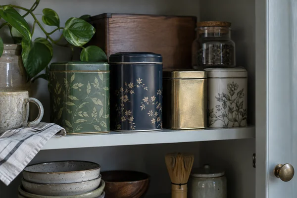 Cool shaded cupboard with closed tea tins away from a kitchen stove