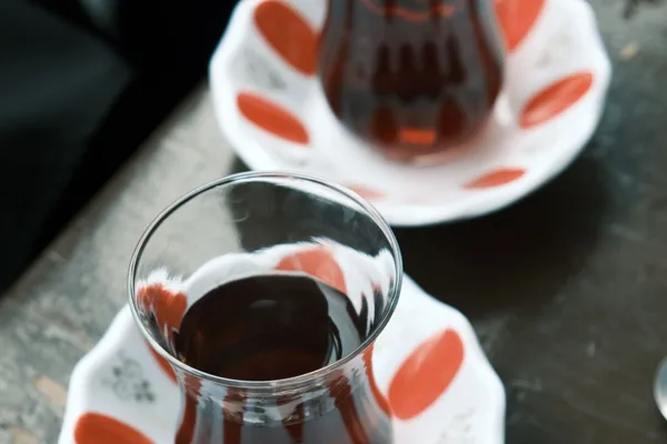 Two Turkish tea glasses on red and white saucers